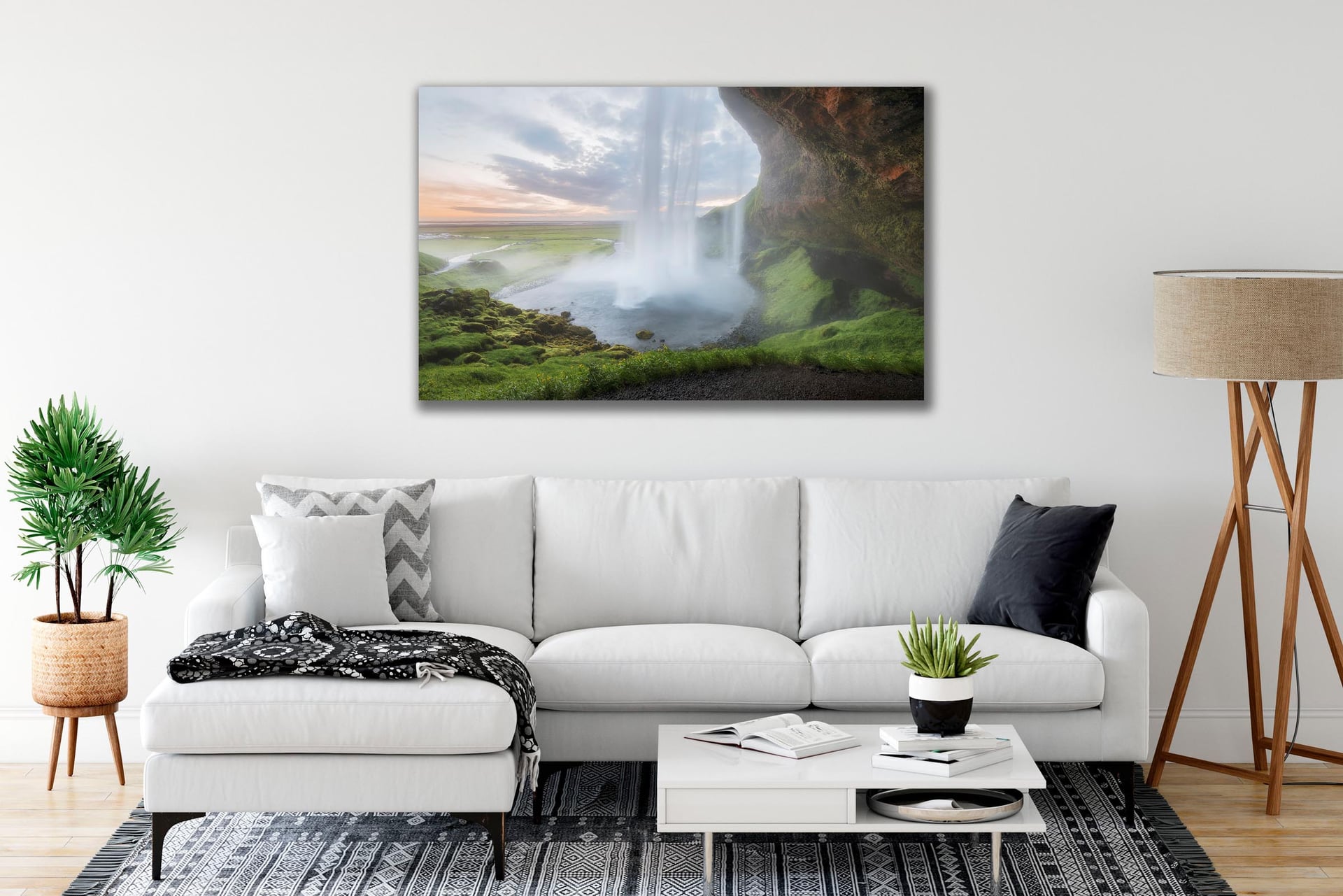 An Iceland waterfall print hanging above a white sofa in a bright, airy living room