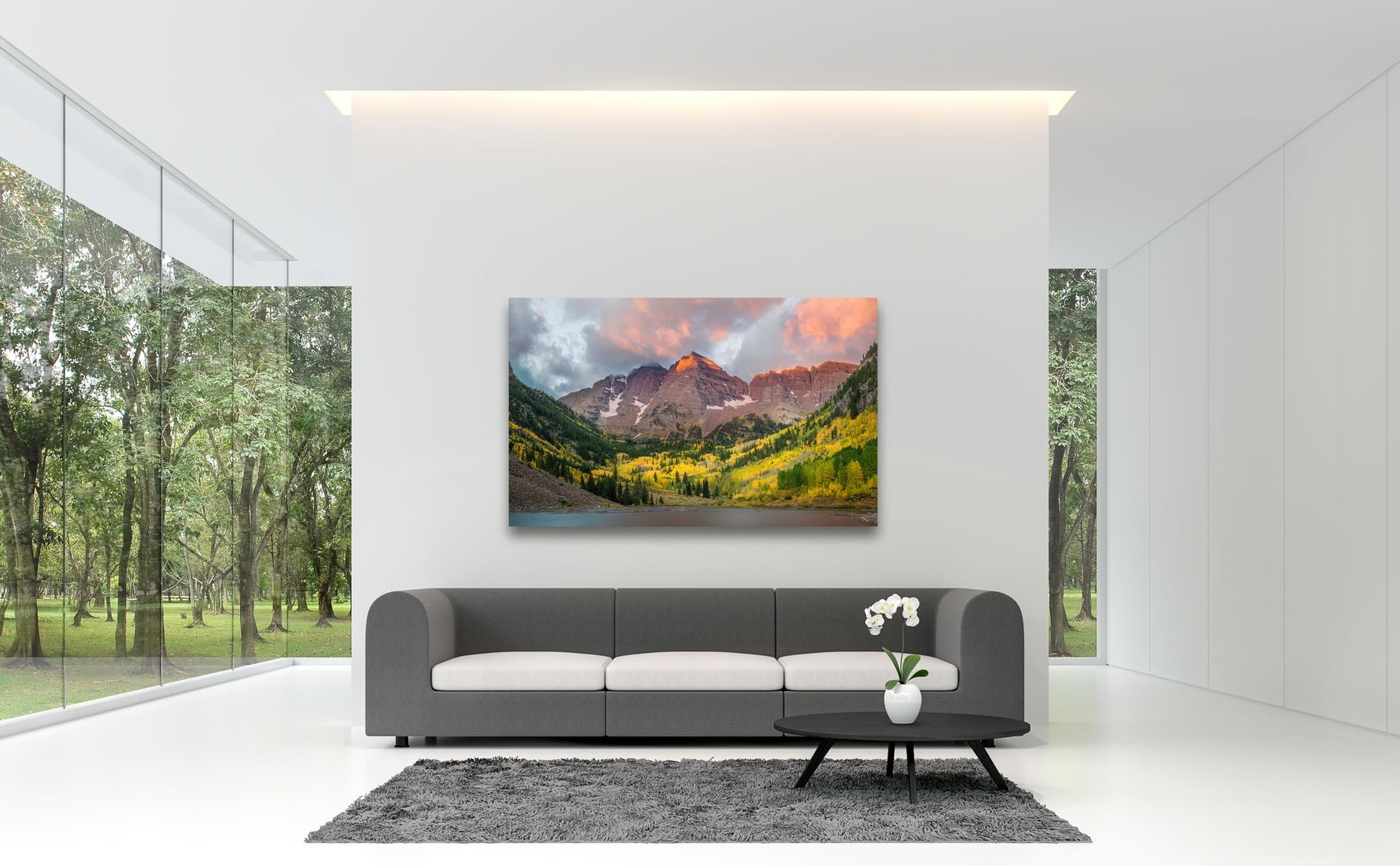 A mountain sunrise print previewed above a sofa in a minimalist white room